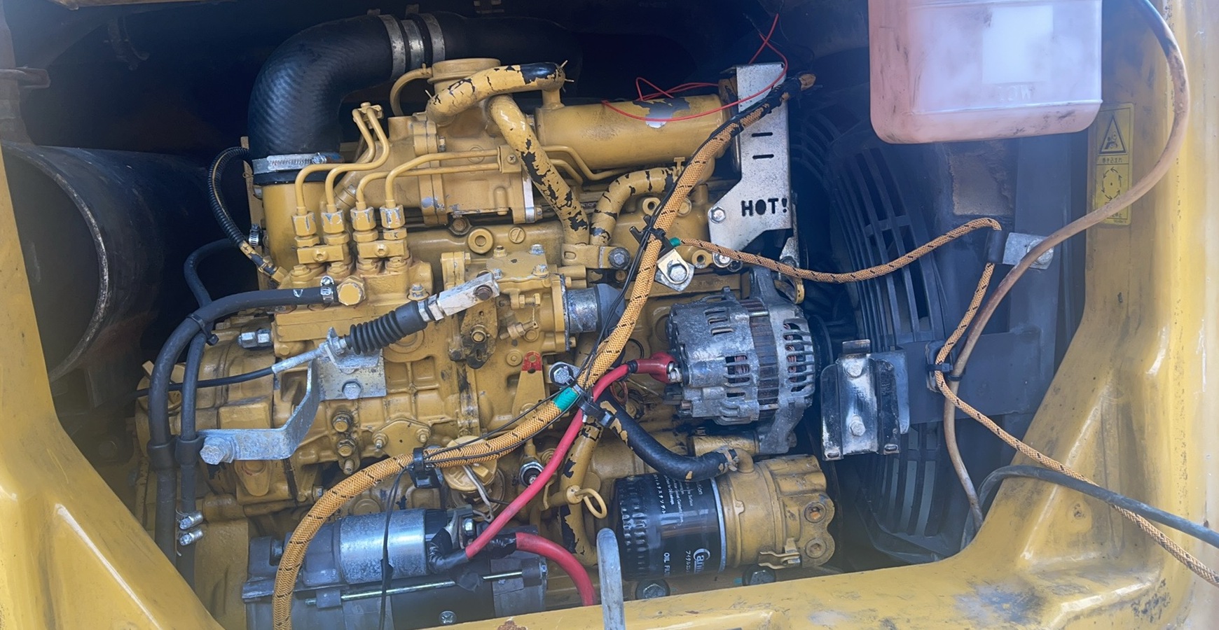 A yellow engine bay with installed starter, alternator, cables, hoses and access space.
