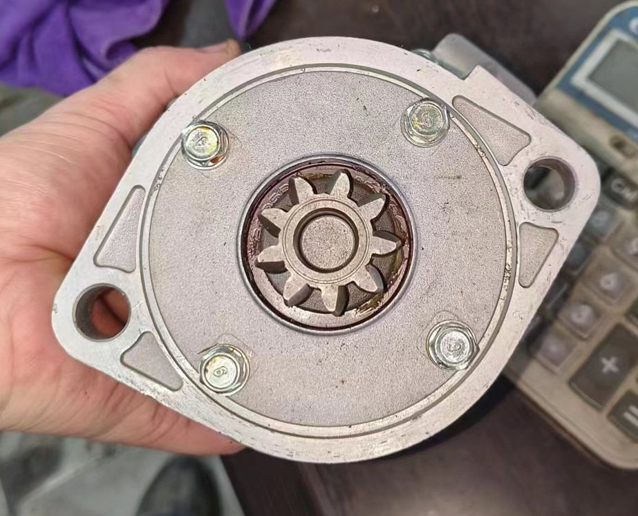 Hand-held starter drive end showing a gear outline, mounting face and two mounting openings.