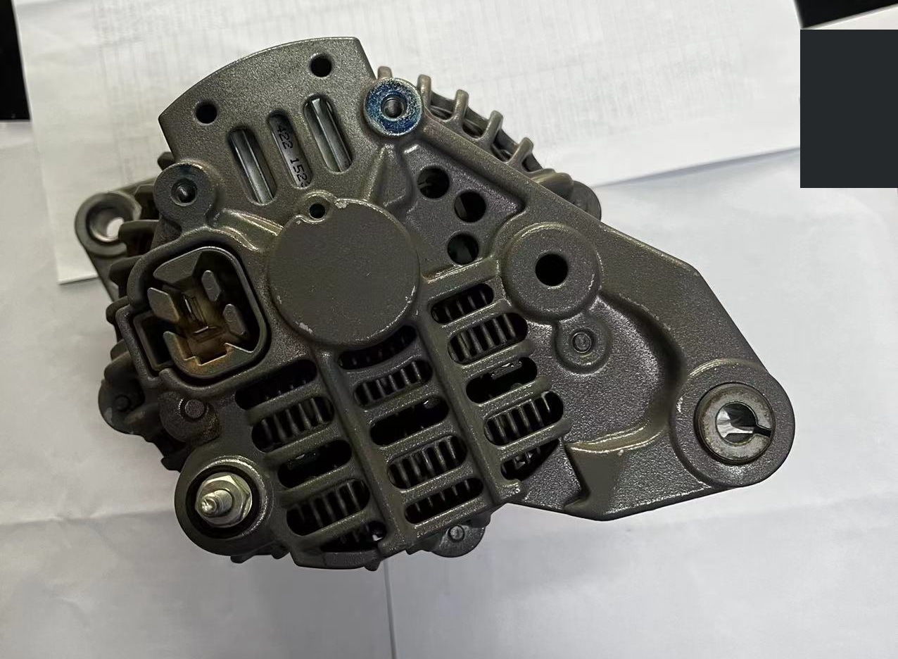 A removed alternator rear view with connector, terminals, mounting ears and a background corner mask.